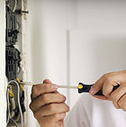 Man using screwdriver on electric breaker box, close-up